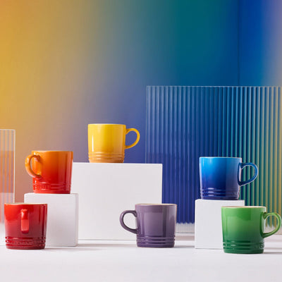 Colorful mugs on a white surface with a gradient background