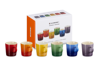 Set of colorful mugs in front of their packaging box on a white background