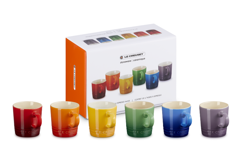 Set of colorful mugs in front of their packaging box on a white background