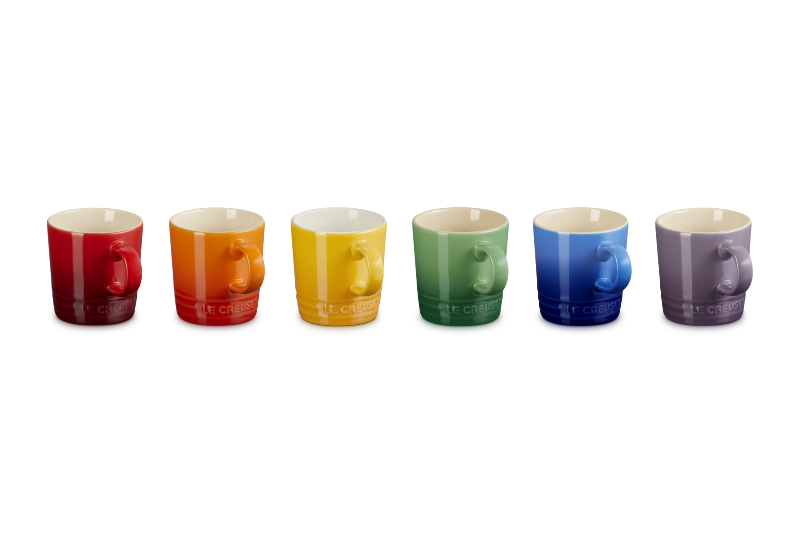 Set of seven colorful mugs arranged in a row on a white background