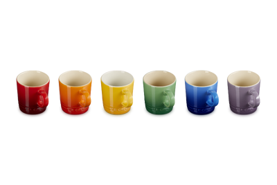 Set of six colorful mugs arranged in a row on a white background