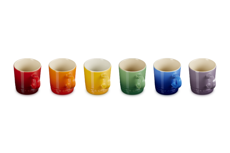 Set of six colorful mugs arranged in a row on a white background