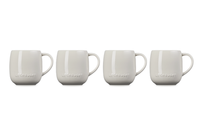 Four white mugs with 'Le Creuset' branding on a white background
