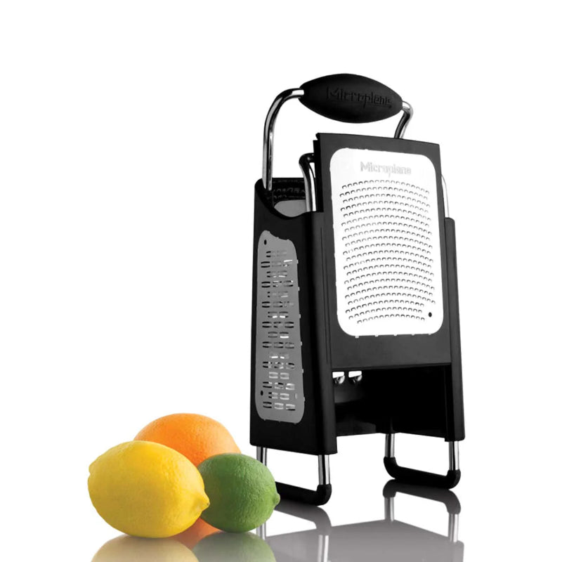 Black Microplane zester with a white label next to lemons and an orange on a white background