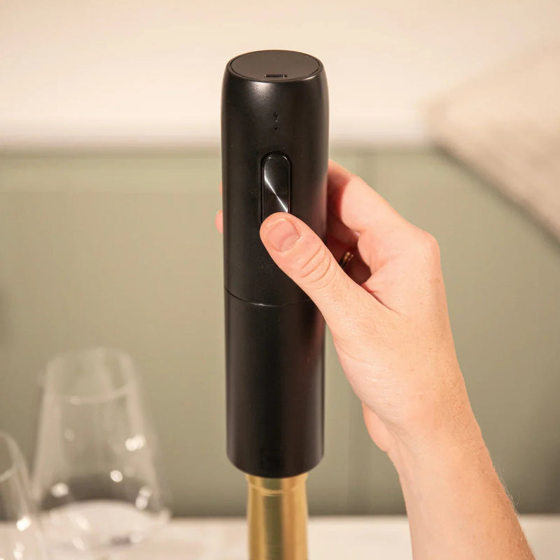 Hand holding a black wine bottle opener with a blurred background